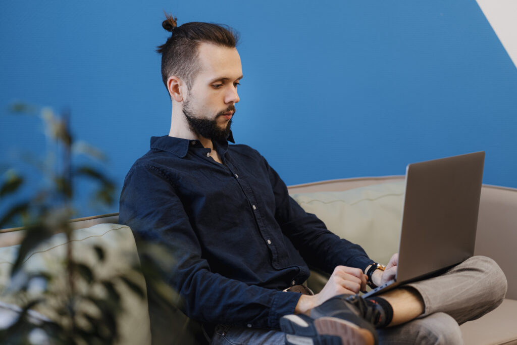 young-man-working-laptop-while-sitting-sofa-office